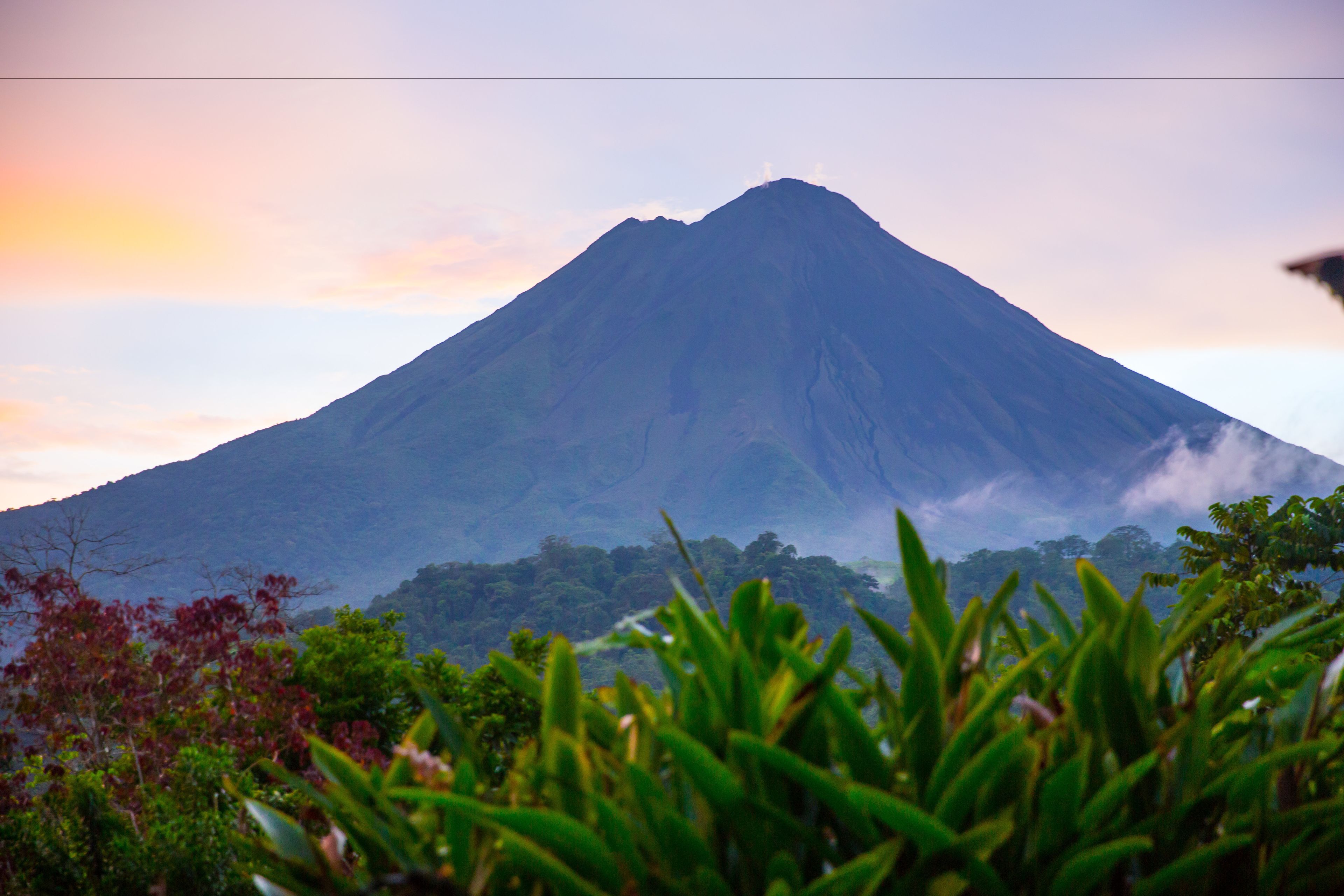 Volcán Arenal al amanecer con cielo rosado visto desde Hotel Kokoro, La Fortuna